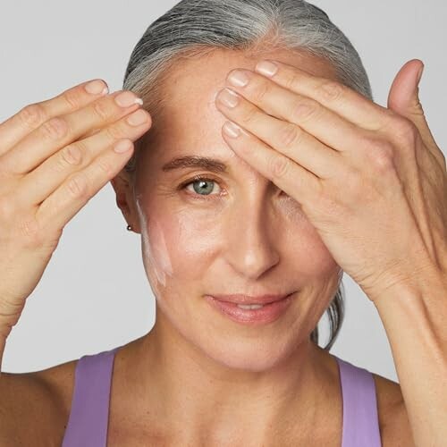 Woman applying face cream to her forehead.