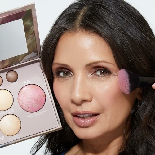 Woman applying makeup with a brush, holding a palette.